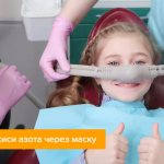 Photo of a small patient in a dentist&#39;s chair, with a nitrous oxide mask on her face